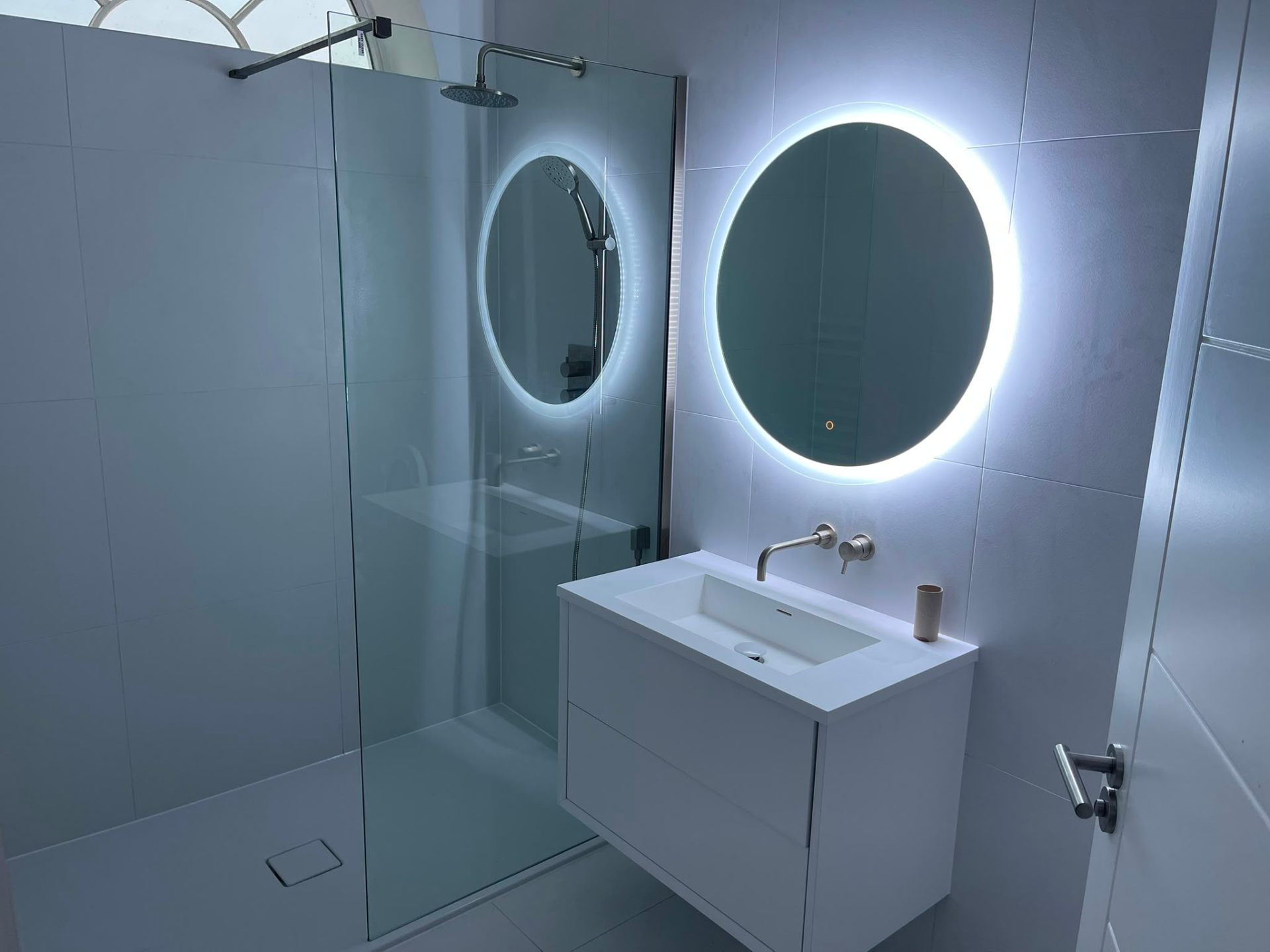 Grey marble bathroom installation with backlit round mirror and vanity unit in Ashford