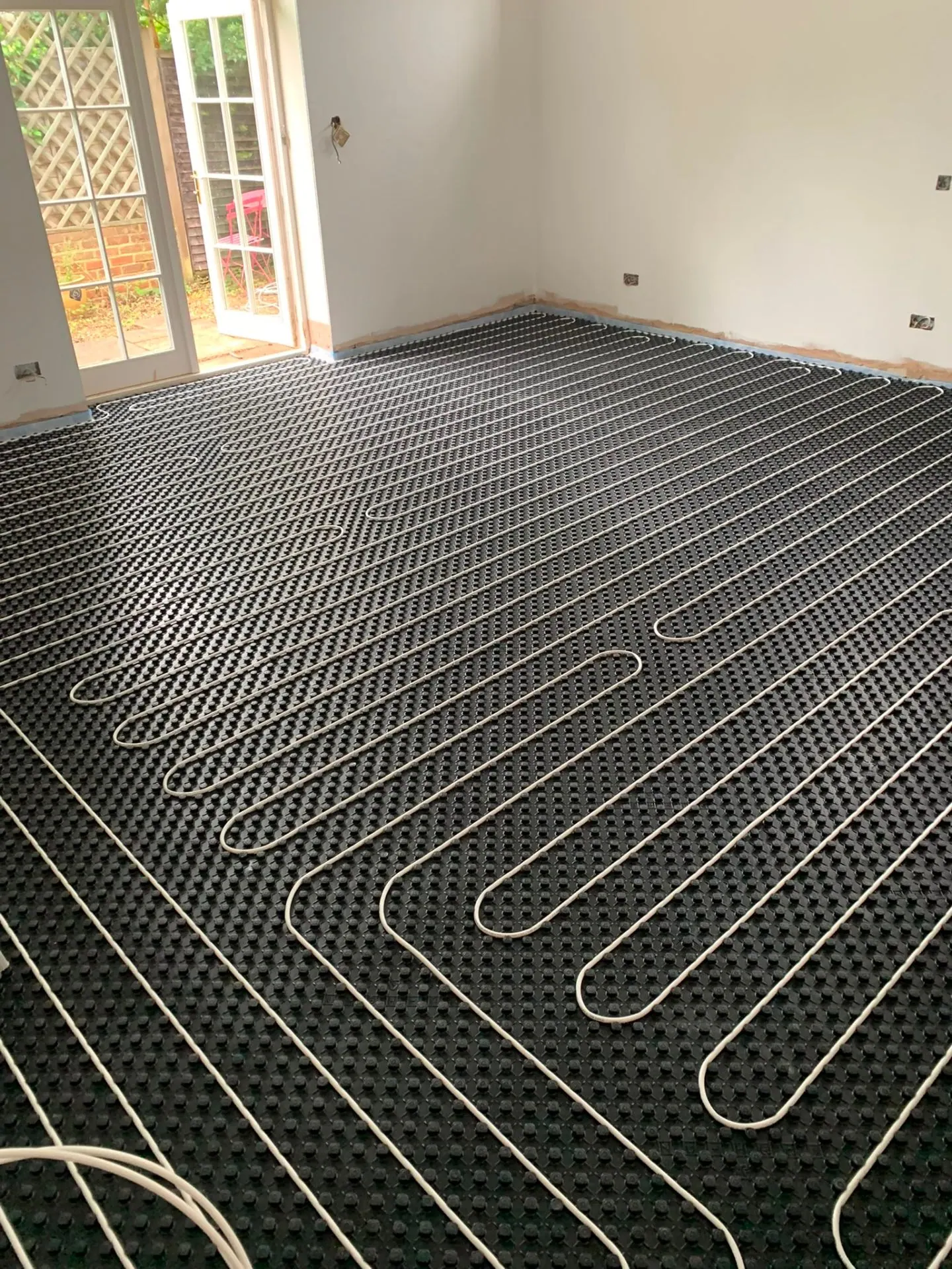 Wet underfloor heating pipe loops laid on insulated panels in a Surrey kitchen extension