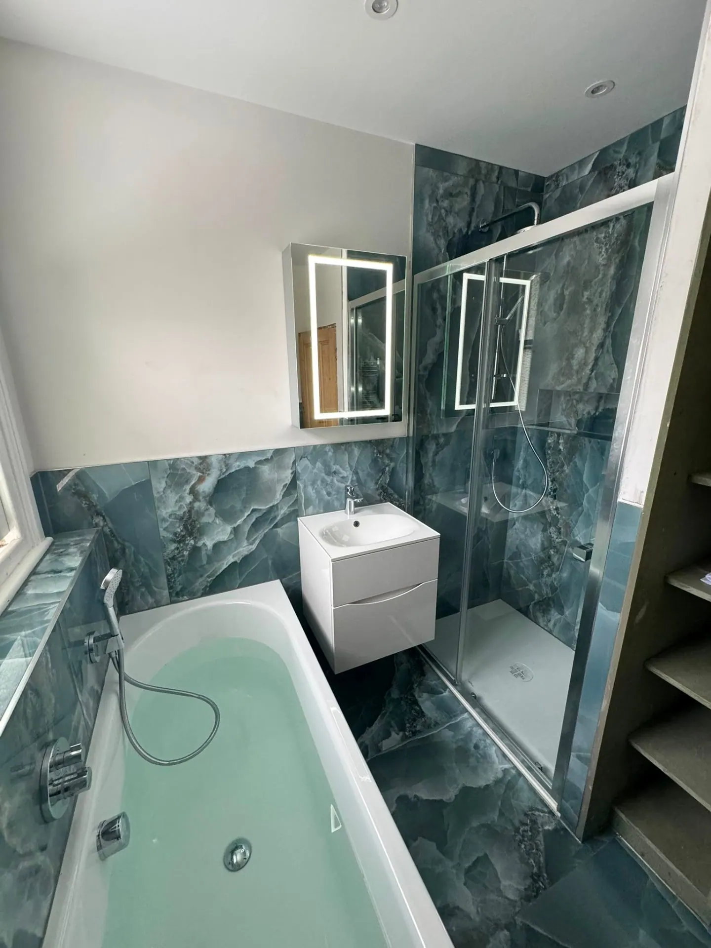 Green marble family bathroom installation with bath and mirror, Ashford
